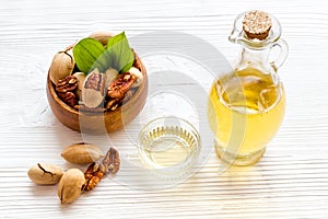 Bottle of pecan oil with nuts on the table, close up