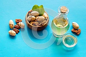 Bottle of pecan oil with nuts on the table, close up