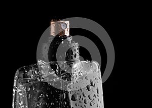 Bottle of perfume with drops of freshness on a black background.