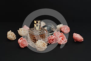 Bottle Perfume and Fake Roses on dark Black Background with copy Space Text