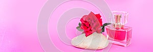 Bottle of perfume, red roses and spa stone in pink background. beauty spa concept copy-space or web banner