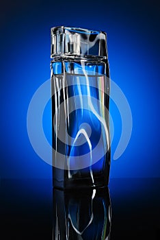 Bottle of perfume with reflection on blue