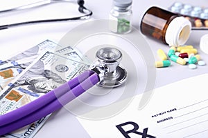 Bottle of pills, dollars banknotes and stethoscope lying on cardiogram chart closeup. medical costs and healthcare