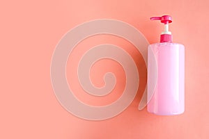 Bottle with pink dishwashing liquid on pink background. Minimal concept