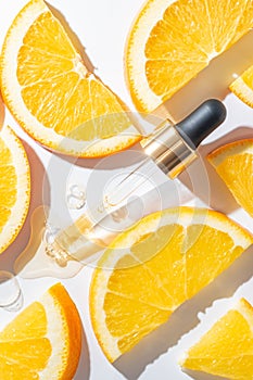 Bottle pipette dropper and Liquid yellow-orange retinol or vitamin c gel or serum on white background with sliced