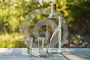 Bottle of Polish vodka with macerated corn ear inside and two glasses.