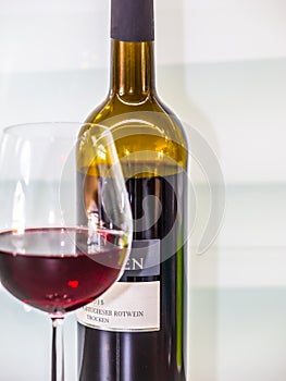 A bottle of Portugues red wine behind a glass filled with red wine in front photo