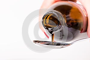 Bottle pouring a liquid on a spoon. Isolated on a white background. Pharmacy and healthy background. Medicine. Cough and cold drug