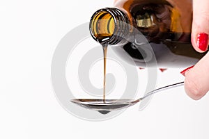 Bottle pouring a liquid on a spoon. Isolated on a white background. Pharmacy and healthy background. Medicine. Cough and cold drug