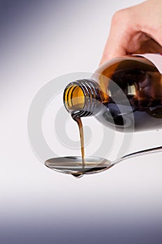 Bottle pouring a liquid on a spoon. on a white background. Pharmacy and healthy background. Medicine. Cough and cold drug