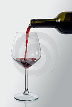 Bottle pouring red wine into an elegant glass