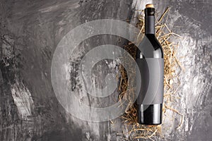 Bottle of red wine with black blank label on black texture. Mock up a bottle of wine. View from above. Flat lay. Black space