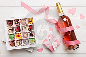 Bottle of red wine on colored background for Valentine Day with gift and chocolate. Heart shaped with gift box of