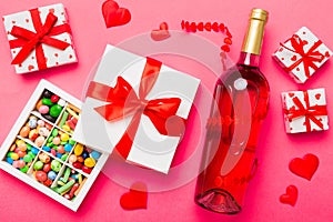 Bottle of red wine on colored background for Valentine Day with gift and chocolate. Heart shaped with gift box of
