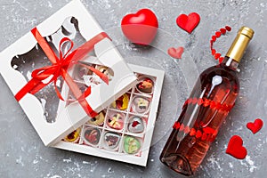 Bottle of red wine on colored background for Valentine Day with gift and chocolate. Heart shaped with gift box of