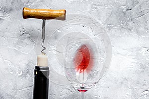 Bottle of red wine with corkscrew on white stone background