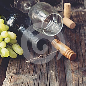 Bottle of red wine with fresh grape and bunch of corks on wooden table