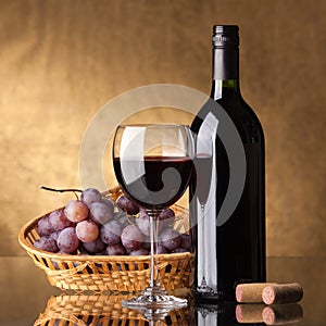 A bottle of red wine, glass