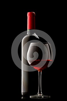Bottle with red wine and glass on a black
