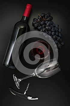 Bottle of red wine, glass, corkscrew  and ripe grapes