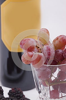 Bottle of red wine, and glass filled with grapes