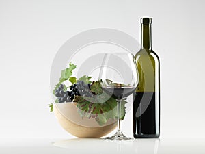 Bottle red wine, glass, grapes white background