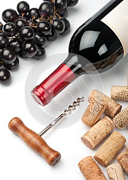 Bottle of red wine, grapes, corkscrew and corks