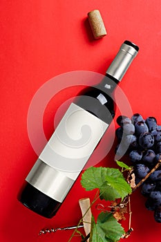 Bottle of red wine with a label, grapes and a cork. Wine bottle mockup.
