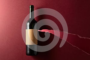 Bottle of red wine with old empty label on a dark red background