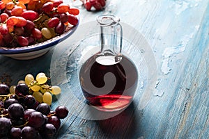 Bottle of red wine and ripe grapes on a wooden table.