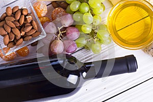 Bottle of red wine with snacks - various types of cheese, figs, nuts, honey, grapes on a wooden boards background