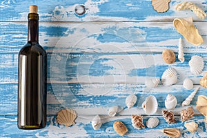 Bottle of red wine on vintage blue wooden board with seashells