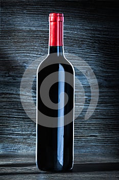 Bottle of red wine on vintage wood background