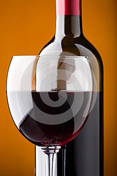 A bottle of red wine and a wine glass closeup