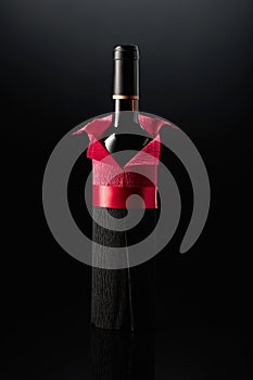 Bottle of red wine wrapped in crepe paper on a black background