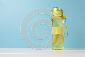 A bottle with a refreshing drink with lemon on a blue background