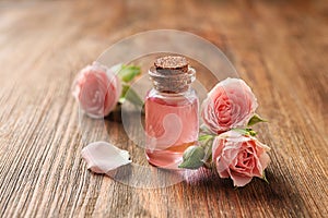 Bottle of rose essential oil and flowers