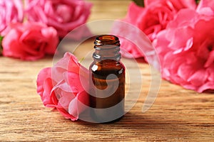 Bottle of rose essential oil and flowers