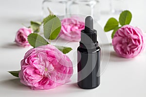 A bottle of rose essential oil with rose flowers