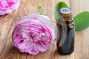 A bottle of rose essential oil with rose flowers in the background