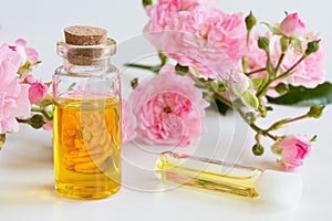 A bottle of rose essential oil with small rose blossoms