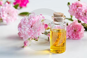 A bottle of rose essential oil with small rose blossoms