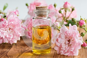 A bottle of rose essential oil with small rose blossoms