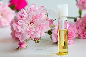 A bottle of rose essential oil with small rose blossoms