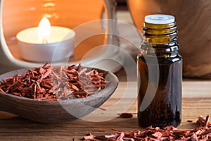 A bottle of sandalwood essential oil with sandalwood pieces photo