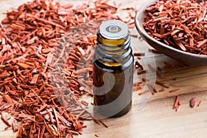 A bottle of sandalwood essential oil with sandalwood on a wooden photo