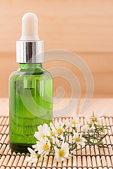 Bottle serum for beauty Spa and therapy treatment wiht wildflowers on wooden background.
