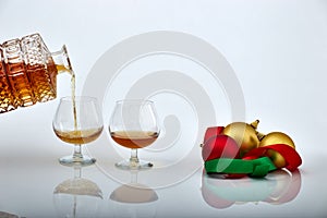 Bottle serving in a glass of liquor with Christmas ornaments, white backgrounds and reflections