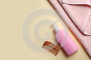 Bottle with shampoo, towel and comb on color background, flat lay.