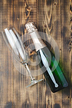 Bottle of sparkling wine and a glass on a wooden background. Top view